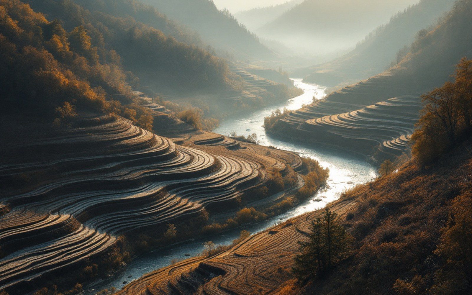 A steep river valley with terraced slopes, haze